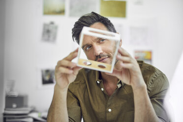 Portrait of man checking component in his office - PNEF00336