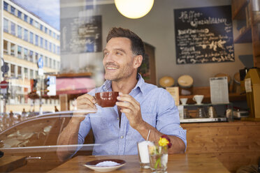Portrait of laghing man with cup of coffee in a coffee shop - PNEF00339
