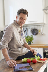 Portrait of man using tablet in the kitchen - PNEF00346