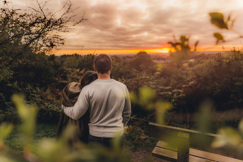 Rückenansicht eines verliebten Paares in herbstlicher Natur bei Sonnenuntergang, lizenzfreies Stockfoto