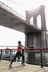 Woman doing stretching exercises in Manhattan near Brooklyn Bridge in the morning - GIOF03326