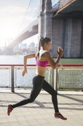 Woman doing stretching exercises in Manhattan near Brooklyn Bridge in the morning - GIOF03327