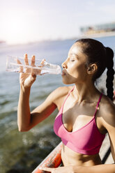 Aktive Frau trinkt Wasser aus einer Trinkflasche - GIOF03331