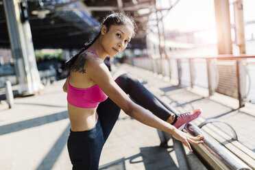 Woman doing stretching exercises in Manhattan near Brooklyn Bridge in the morning - GIOF03335