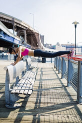Weibliche Athletin trainiert in Manhattan in der Nähe der Brooklyn Bridge, macht Liegestütze auf dem Geländer - GIOF03342