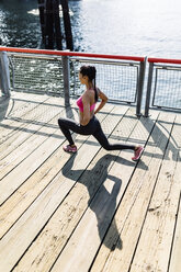Woman doing stretching exercises in Manhattan near Brooklyn Bridge in the morning - GIOF03345