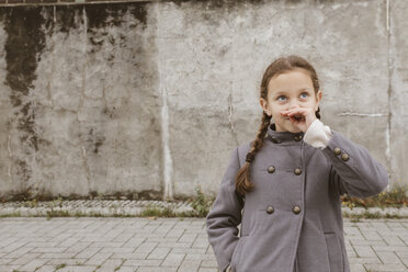 Portrait of little girl with braids wearing grey coat - KMKF00063