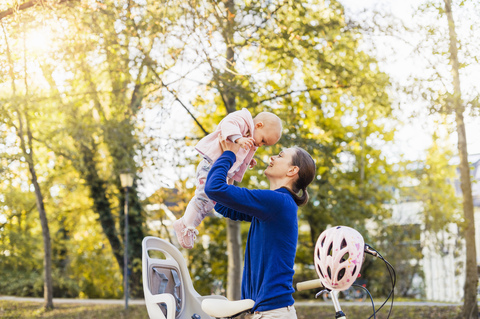 Mutter und Tochter fahren Fahrrad, heben das Baby aus dem Kindersitz, lizenzfreies Stockfoto