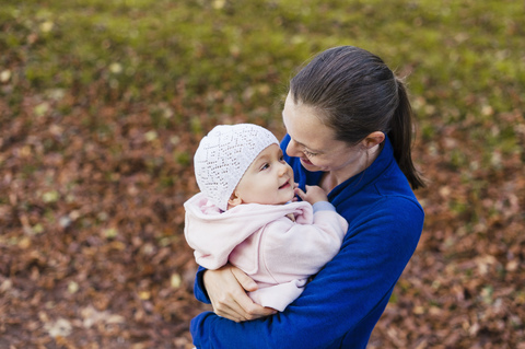 Mother hugging daughter in autumnal park stock photo