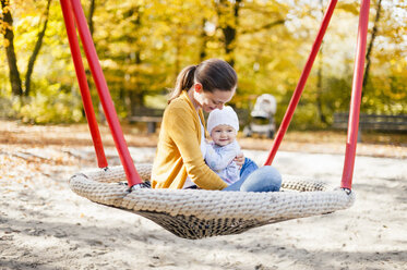 Happy baby girl relaxing with her mother on a swing in autumn - DIGF03194