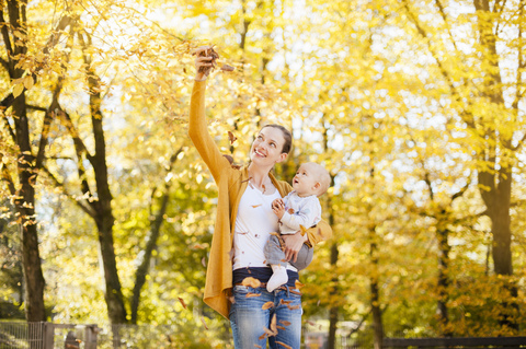 Mutter und kleines Mädchen haben Spaß mit Blättern im Herbst, lizenzfreies Stockfoto