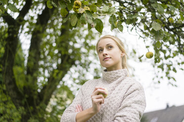 Porträt einer jungen Frau am Apfelbaum im Garten - JOSF01883