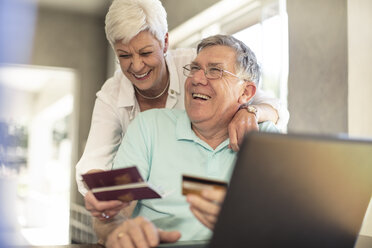 Happy senior couple holding passports booking their trip together online - ZEF14746