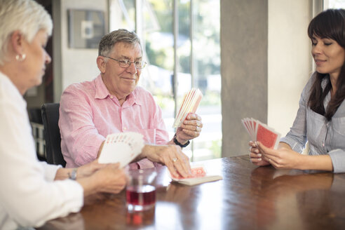Senior couple playing cards with daughter at home - ZEF14761