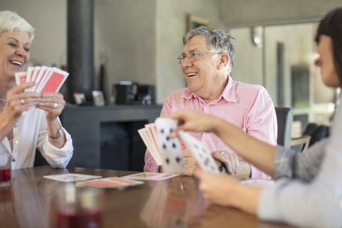 Älteres Paar spielt Karten mit Tochter zu Hause, lizenzfreies Stockfoto