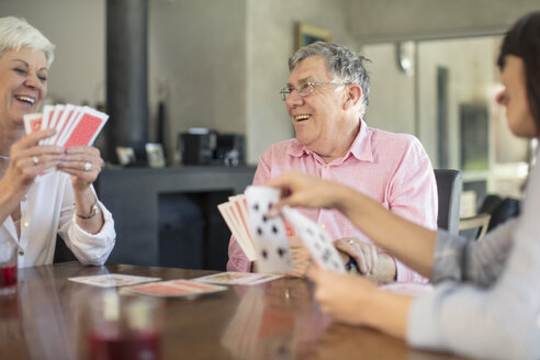 Senior couple playing cards with daughter at home - ZEF14763