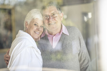 Portrait of smiling senior couple behind windowpane - ZEF14766