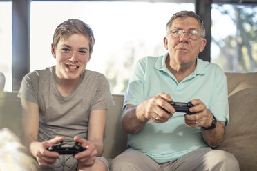 Großvater und Enkel spielen ein Videospiel auf der Couch zu Hause - ZEF14779