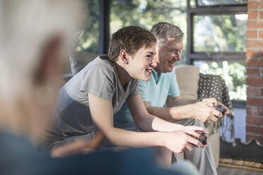 Großvater und Enkel spielen ein Videospiel auf der Couch zu Hause - ZEF14780