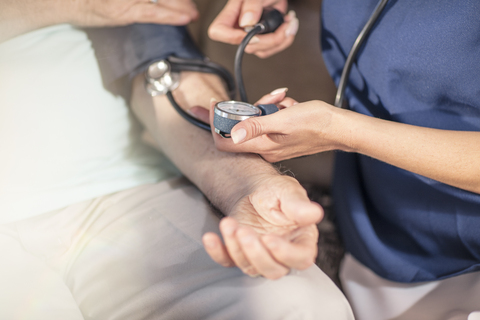 Krankenschwester misst Blutdruck eines älteren Patienten zu Hause, lizenzfreies Stockfoto
