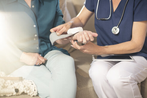 Nurse taking blood pressure of senior patient at home - ZEF14786