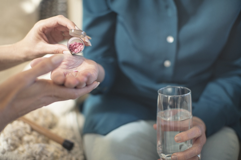 Nurse giving medication to senior woman at home stock photo