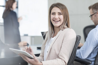 Portrait of laughing businesswoman with tablet on a meeting in conference room - ZEF14797