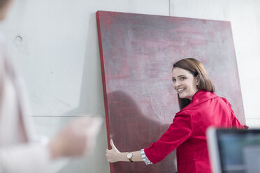 Businesswoman in office holding a red painting - ZEF14816