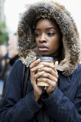 Porträt einer modischen jungen Frau mit Kaffee zum Mitnehmen und Kapuzenjacke - MAUF01219