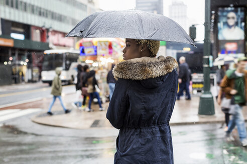 USA, New York City, junge Frau mit Regenschirm an einem regnerischen Tag - MAUF01226