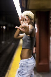 USA, New York City, Frau auf dem Bahnsteig einer U-Bahn-Station zeigt Handfläche - MAUF01231