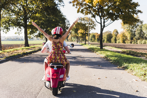 Carefree young couple riding motor scooter on country road stock photo