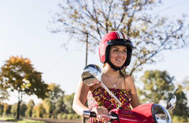 Porträt einer lächelnden jungen Frau auf einem Motorroller - UUF12274