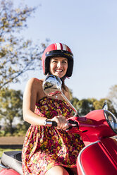 Porträt einer glücklichen jungen Frau auf einem Motorroller - UUF12275