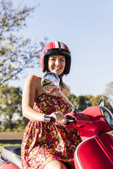 Portrait of happy young woman on motor scooter - UUF12275