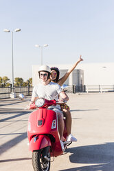 Unbekümmertes junges Paar fährt Motorroller auf Parkebene - UUF12285