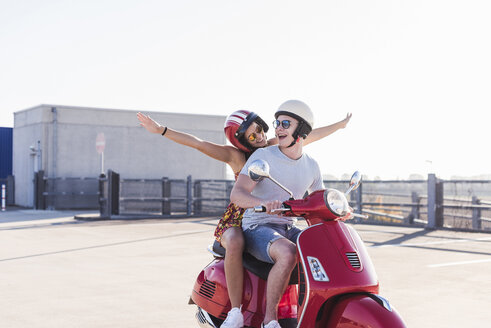 Unbekümmertes junges Paar fährt Motorroller auf Parkebene - UUF12286