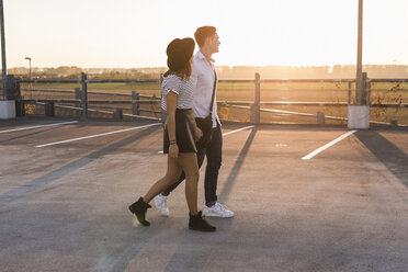 Junges Paar geht Hand in Hand auf dem Parkdeck bei Sonnenuntergang - UUF12305