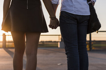 Junges Paar Hand in Hand auf dem Parkdeck bei Sonnenuntergang - UUF12310