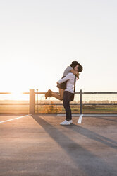 Young couple hugging on parking level at sunset - UUF12313