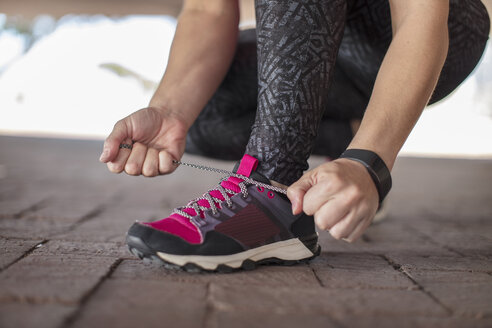 Sportliche Frau bindet sich die Schuhe - ZEF14825