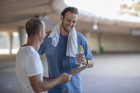 Glücklicher sportlicher Mann mit seinem Fitnesstrainer nach dem Training, lizenzfreies Stockfoto