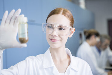 Smiling scientist in lab examining sample - WESTF23690