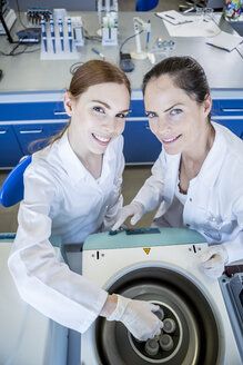 Porträt von zwei lächelnden Wissenschaftlern an einer Maschine im Labor - WESTF23717