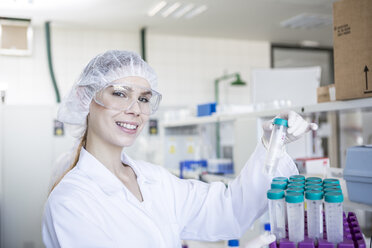 Porträt eines lächelnden Wissenschaftlers im Labor mit Reagenzglas - WESTF23735