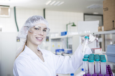 Portrait of smiling scientist in lab holding test tube - WESTF23735