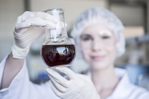 Scientist in lab holding flask with liquid - WESTF23738