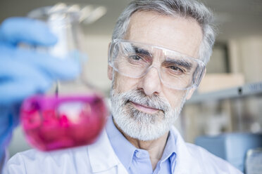 Scientist in lab holding beaker with liquid - WESTF23739