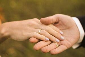 Brautpaar hält sich an den Händen, zeigt Eheringe - FCF01304