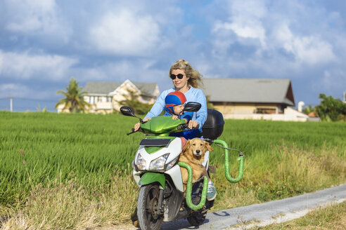 Frau mit Kind und Hund auf einem Motorroller auf einem Feldweg - KNTF00920